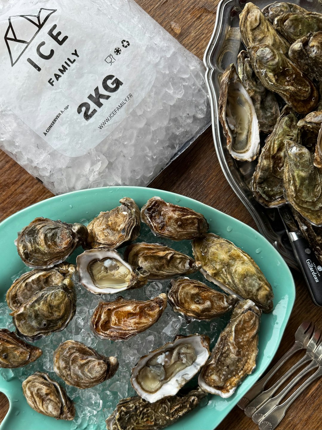 Fresh oysters on crushed ice with shucking tools on a table.