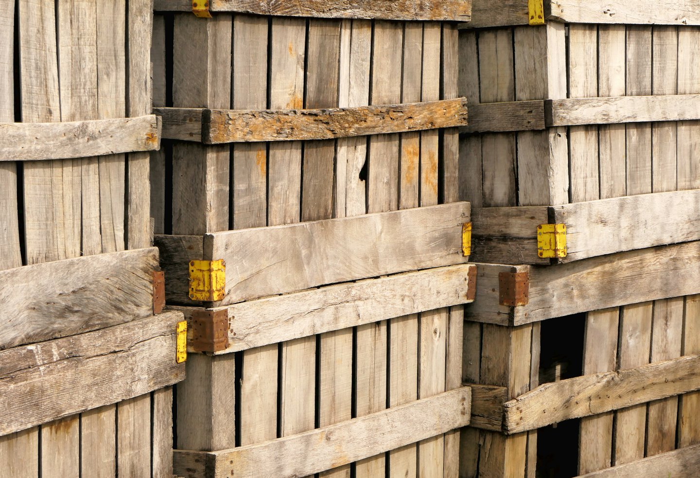 Weathered wooden crates with yellow metal brackets stacked together.