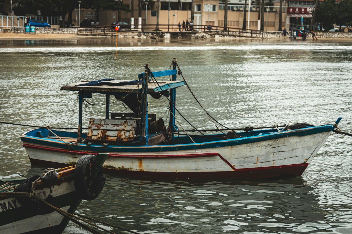 Two weathered wooden fishing boats float in choppy water.